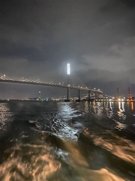 the bridge is lit up at night time as seen from the water's edge