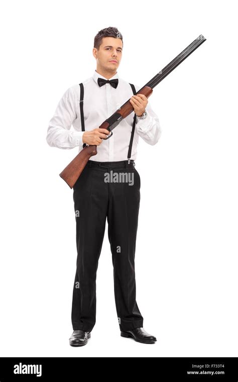 Full length portrait of an armed young man holding a shotgun rifle and looking at the camera ...