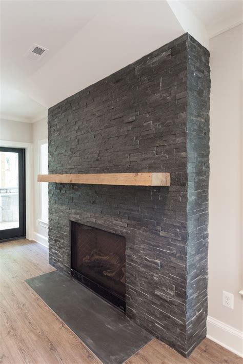 Black stacked stone fireplace with reclaimed natural wood coat in walk ...