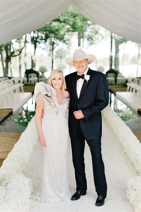 a man and woman standing next to each other in front of a white wedding ...