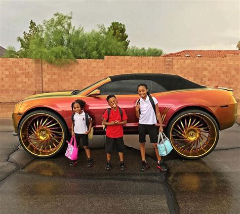 Download Three Children Standing Next To A Car With Large Wheels Wallpaper | Wallpapers.com