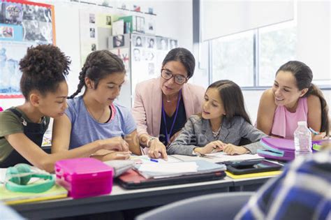 Female teacher and junior high school students studying at desk in ...