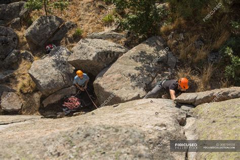 Adventurers climbing mountain, wearing safety harness against ...