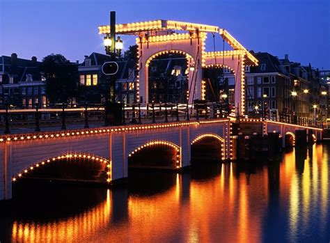 The most famous bridge in Amsterdam is probably the Magere Brug, a white wooden bridge over the ...