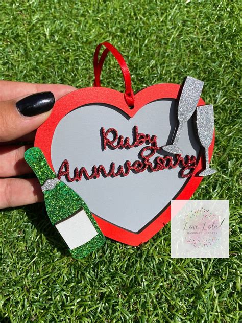 a hand holding a heart shaped ornament that says ruby anniversary