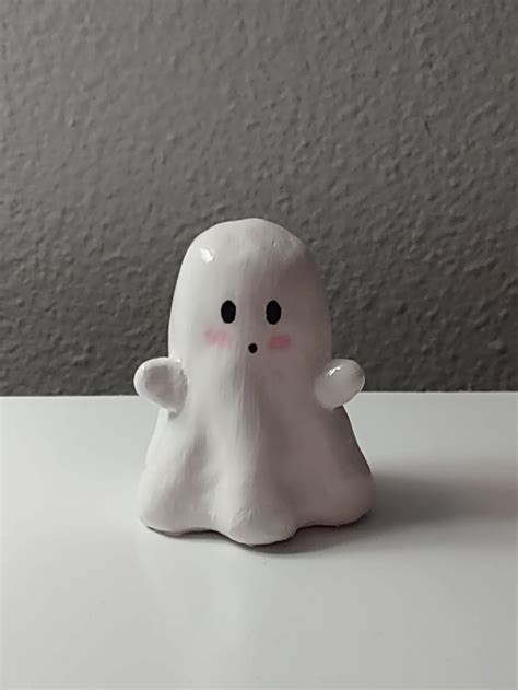 a white ghost figurine sitting on top of a table next to a wall