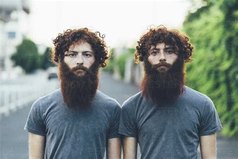 Portrait of identical adult male twins with red hair and beards on sidewalk stock photo