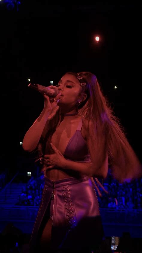 a woman with long hair in a purple outfit singing into a microphone at ...