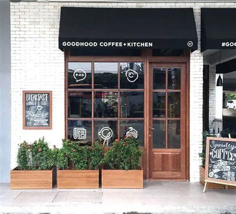 the outside of a coffee shop with wooden planters and chalkboards on the windows