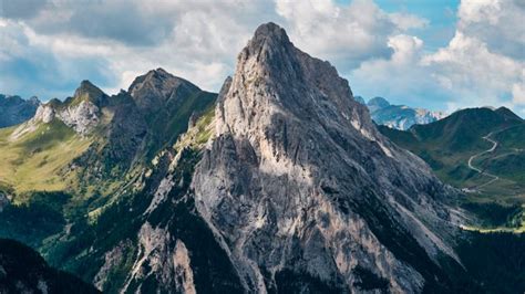 the mountains are covered with green grass and clouds in the distance ...