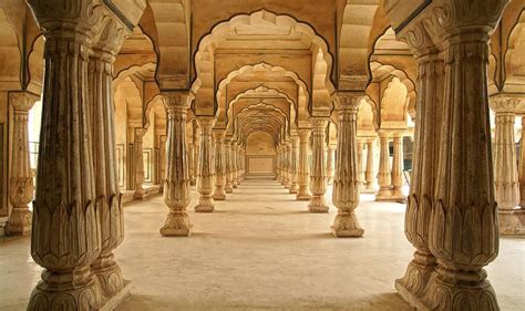 the inside of an old building with columns and arches on either side of the walkway