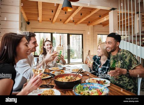 Group of cheerful young friends having dinner and laughing at the table ...