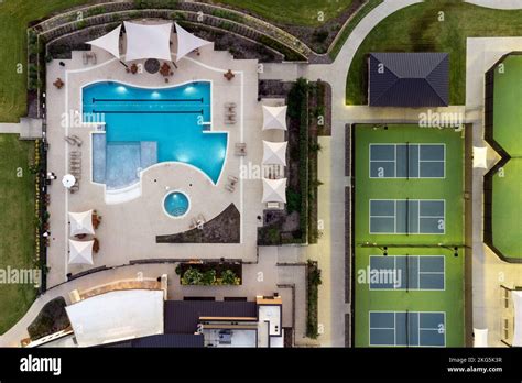 Aerial view of large tennis courts, swimming pool at community recreational center with mansions ...