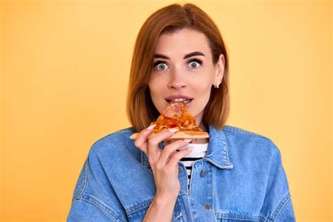 Premium Photo | Young woman eating pizza slice and looking delighted person