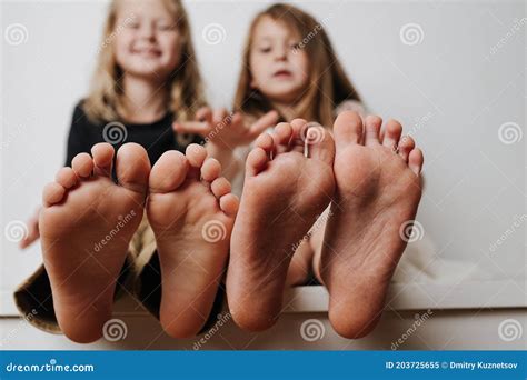 Kids Hold Feet Close Up To the Camera. Their Blurred Faces in a Background. Stock Image - Image ...