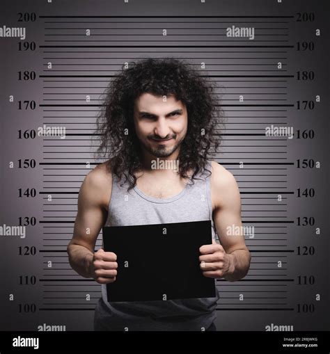 Criminal mugshot. Arrested man with blank card against height chart Stock Photo - Alamy