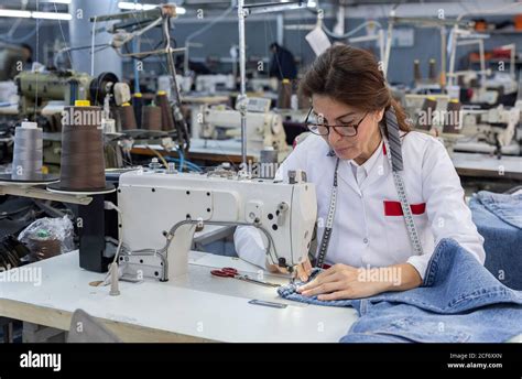 Working Woman hands in textile factory sewing on industrial sewing machine. Industrial ...