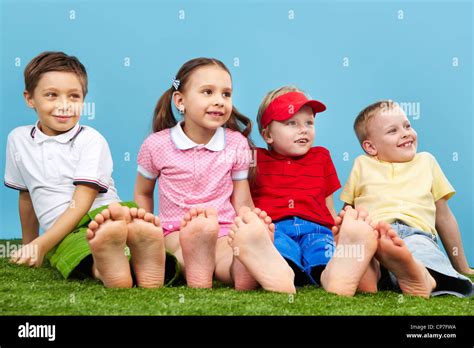 Happy children sitting on the grass barefoot Stock Photo - Alamy