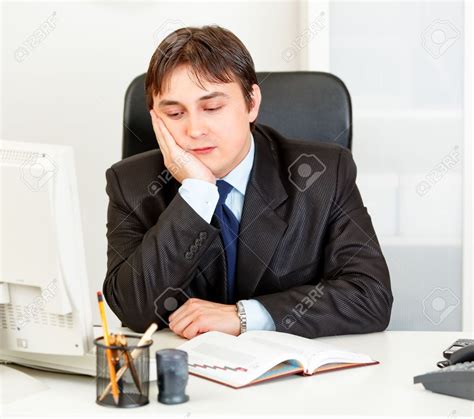 Bored Modern Business Man Sitting At Desk In Office Stock Photo ...