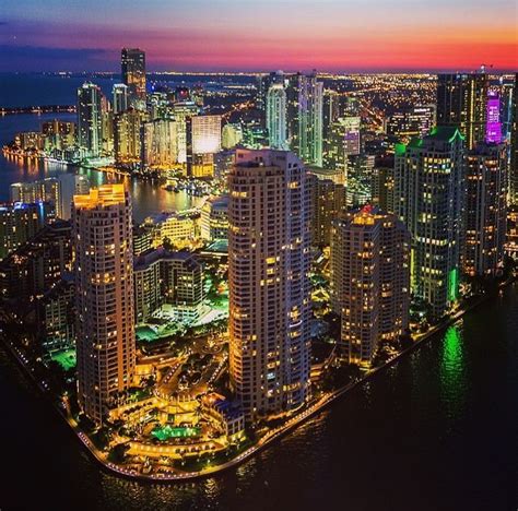 an aerial view of a city at night with the lights on and buildings lit up