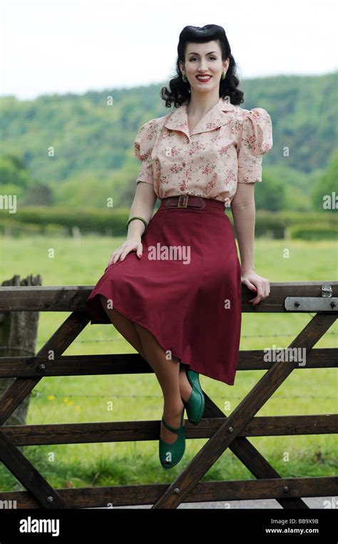 Woman in old fashioned clothing sitting on gate Stock Photo - Alamy