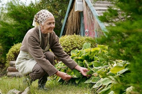 Premium Photo | Senior woman in casualwear sitting on squats while working in the garden