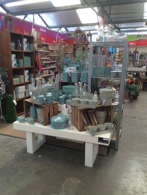 a table with many pots and vases on it in a room filled with shelves