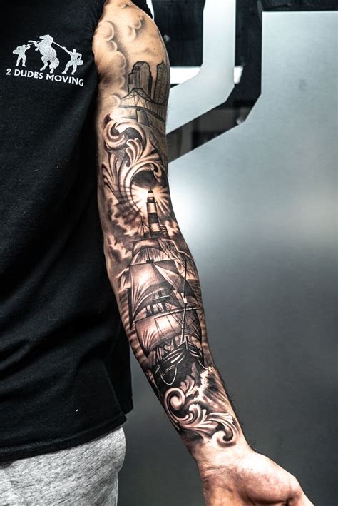 A Ship with a Lighthouse displayed in Black & Grey Realistic Tattoo Work. #tattoos #tattooart # ...