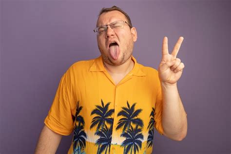 Free Photo | Man in glasses wearing orange shirt sticking out tongue showing v-sign happy and ...