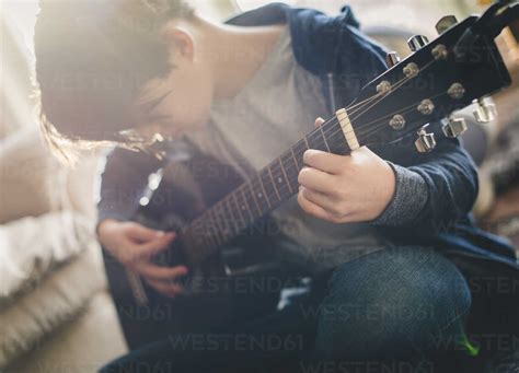 Boy playing guitar at home stock photo