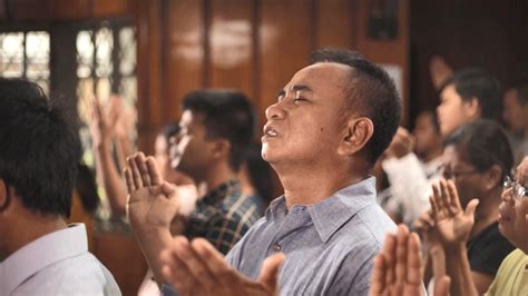 a group of people sitting and standing in front of each other with their hands together