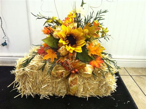 silk flowers nicely arranged on a small hay bale...This would make great decorations for an outd ...
