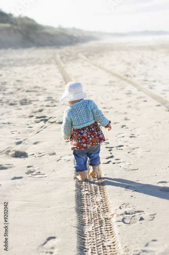 Little girl walking away on the beach Stock Photo | Adobe Stock