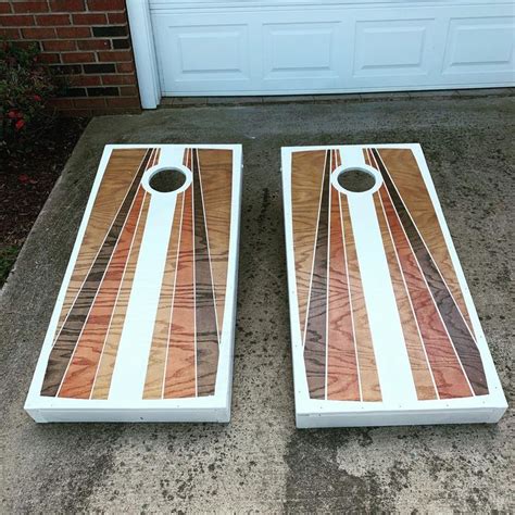 two cornhole game boards sitting on the ground next to a garage door with a white and brown ...