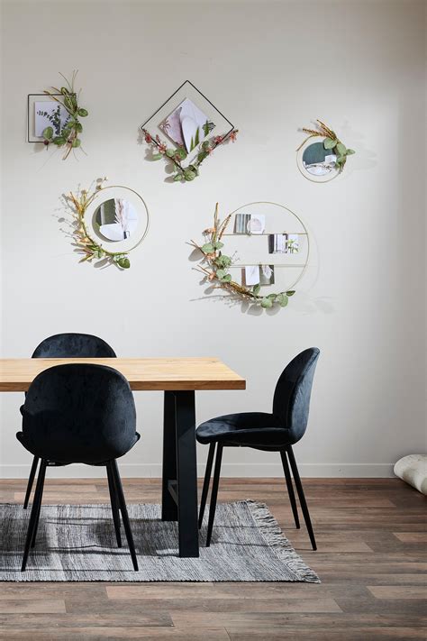 a dining room table with four chairs in front of it and three mirrors on the wall