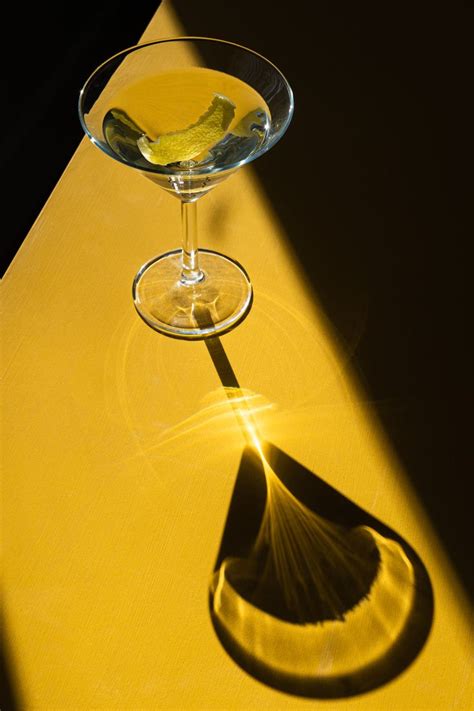 the shadow of a martini glass on a yellow table