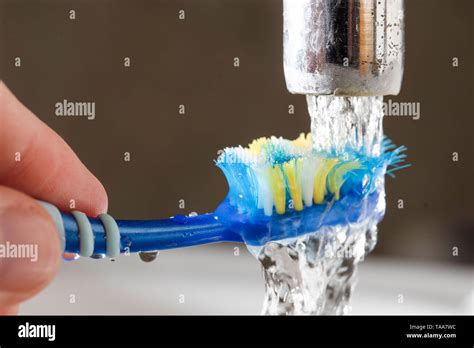 Washing a toothbrush in running tap water - wastage of water Stock Photo - Alamy
