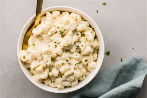 a white bowl filled with macaroni and cheese on top of a blue napkin