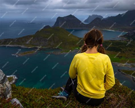 Premium Photo | Girl sits on top of offersoykammen enjoying the panorama of the lofoten islands ...