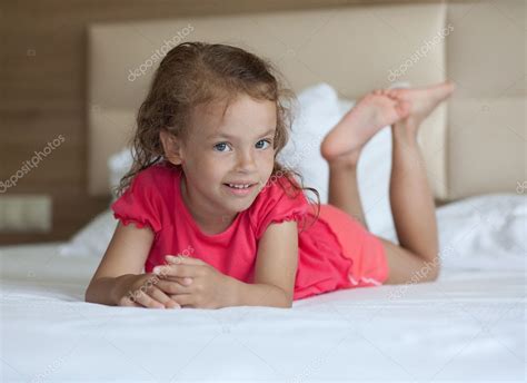 Cheerful little girl lying on the bed. Stock Photo by ©yykkaa 6893947