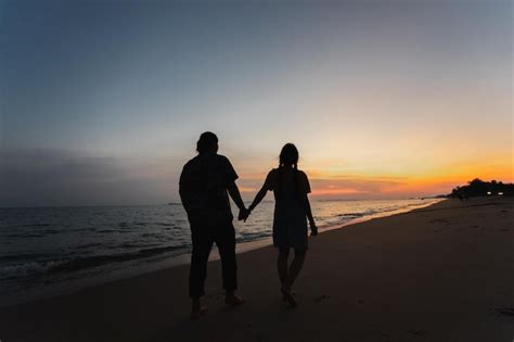 Premium Photo | A couple walking on the beach at sunset