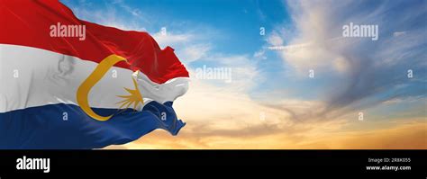 official flag of Labuan Malaysia at cloudy sky background on sunset, panoramic view. Malaysian ...