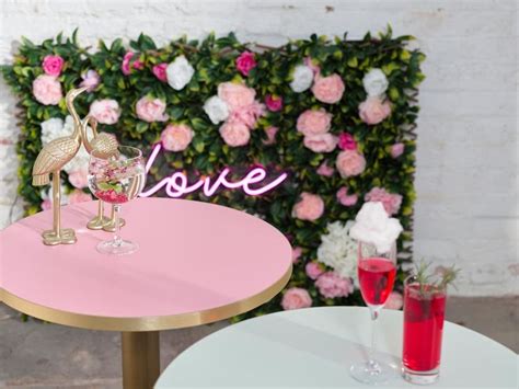 a pink table with two wine glasses on it and a love sign in the background