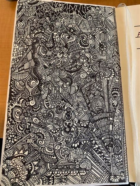 an open book with black and white doodles on the cover sitting on a table