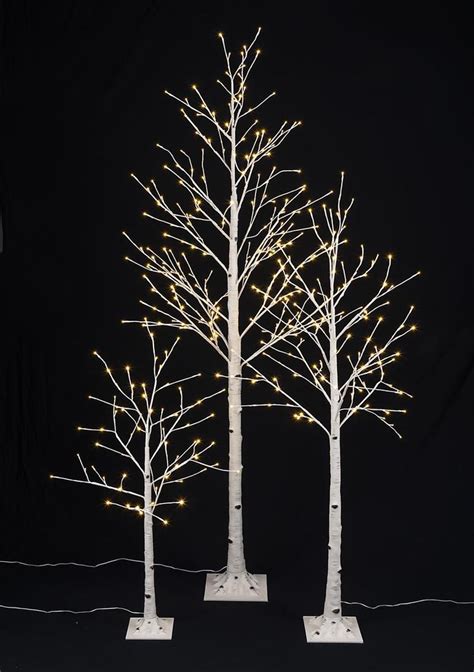 three white trees with lights on them against a black background