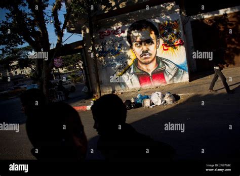 Palestinians walk past a graffiti of a late Palestinian in Gaza city ...