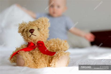 Cute teddy bear sitting up in bed in front of baby girl — Baby Clothes ...