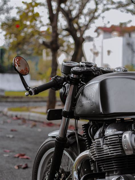 the motorcycle is parked on the side of the road next to the tree lined street