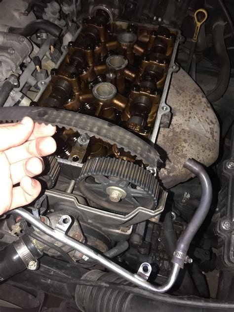 someone is working on an engine in their car, with one hand holding the valve cover