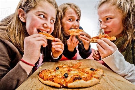 3 teenagers eating pizza - Stock Photo - Dissolve